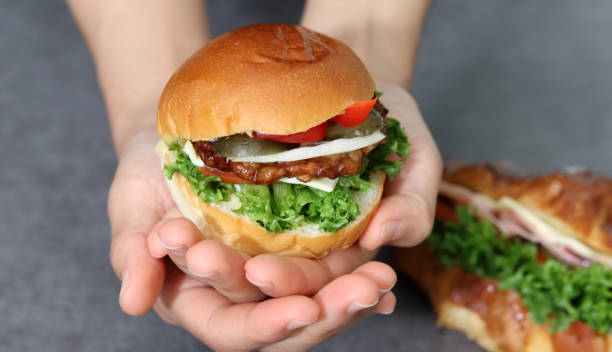 istock Close up image of a hand holding a hamburger. 1721841561