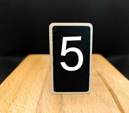 the number five on a wooden background and the color black