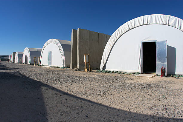 Tent Row "Row of tents providing temporary housing at a major base in Iraq. Also, barriers used to provide protection from mortars." military base stock pictures, royalty-free photos & images