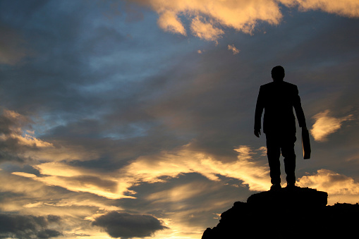 A businessman stands on a mountain.
