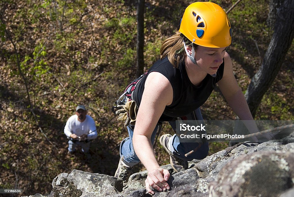 Climbing Girl #3 Female climbing rock with person belaying in background (Focus on Climber) - Adventure Stock Photo