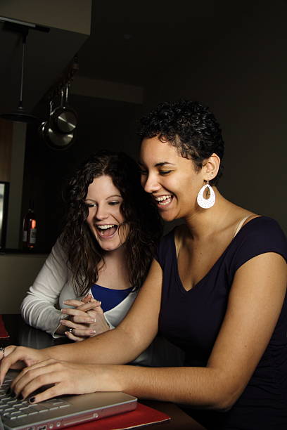 due giovani donne che lavorano su un computer portatile - 20s adult camera caucasian foto e immagini stock