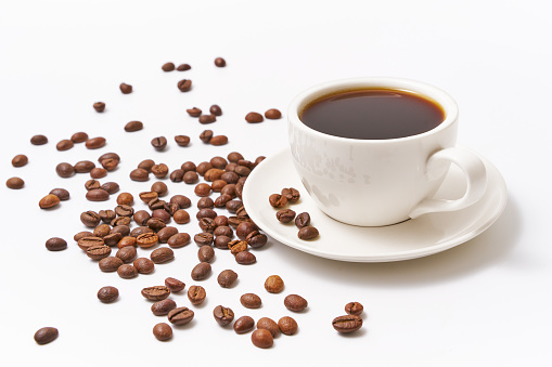 Stock photo showing an elevated food photography image of coffee splashing from espresso cups arranged in a clock face design against a marble effect background. The spilled coffee can be seen as splashing droplets floating in the air.