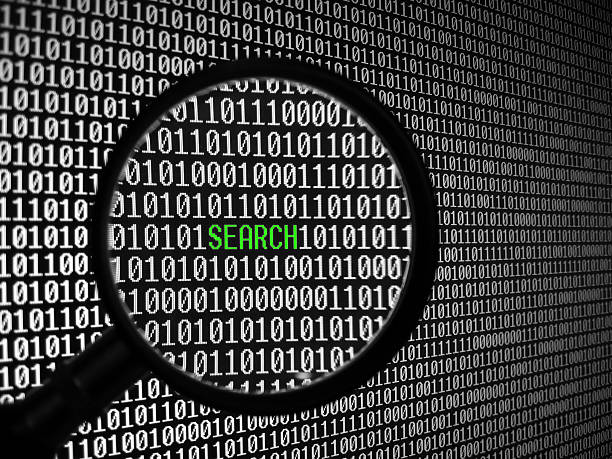 A magnifying glass over a background of binary code stock photo