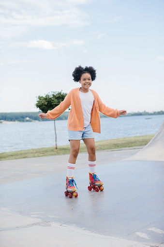 A teenage girl is rollerblading in a summer park. The concept of summer recreation outdoors.