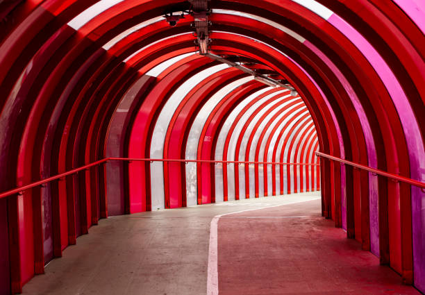 Interior view of the Smartie Tube, the SECC elevated red steel and perspex covered walkway and cycle lane bridging the Clydeside Expressway, giving access to the  Scottish Event Campus (SEC) Glasgow, Scotland, UK Steel and curved perspex covered walkway and cycle path bridging the Clydeside Expressway (A814), giving access to the Scottish Exhibition and Conference Centre (SECC), Glasgow, Scotland, now known as the Scottish Event Campus (SEC). Popular route for taking pedestrians and cyclists from Exhibition Railway Station to the SEC Centre  five interconnected exhibition and meeting spaces, SEC Armadillo and The OVO Hydro and the Clyde.  The bridge is known colloquially as the  Smartie tube and has achieved recognition for its importance as a major city cycle route. perspex stock pictures, royalty-free photos & images