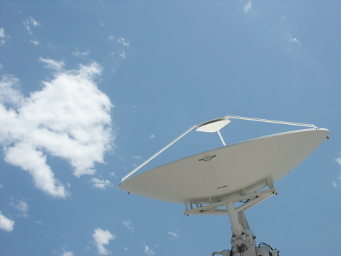 A satellite dish with clouds as a background
