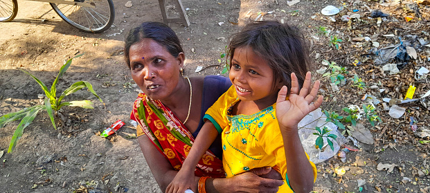 Bihar,India-March 28,2023 : The girl wave goodbye while got hold by her mother at Rajgir in Bihar,India.Every tourist destination in India will see beggar around.