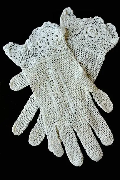 Antique or Old crocheted gloves on black background. Vertical image.