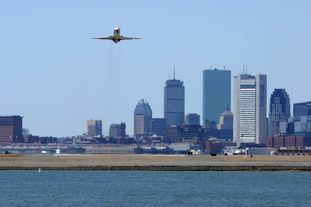 Boston Logan Departure Aircraft departing Boston's Logan International Airport. Boston buildings and skyline in the out of focus background. prudential tower stock pictures, royalty-free photos & images