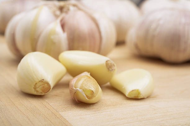 Garlic cloves on a wooden board cloves of garlic onion family stock pictures, royalty-free photos & images