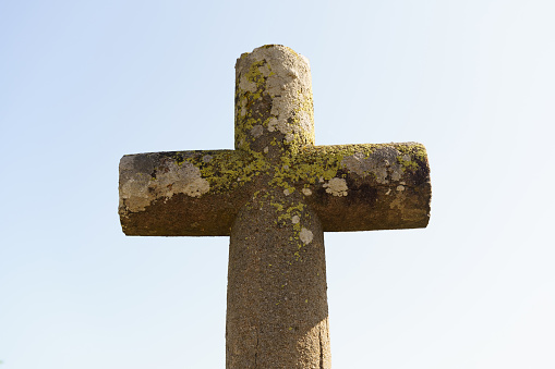 An ancient stone cross under a bright blue sky.