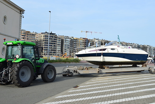 Blankenberge, West-Flanders, Belgium-September 30, 2023: tractor moves a motorboat with a trailer from the marina to a winter storage facility