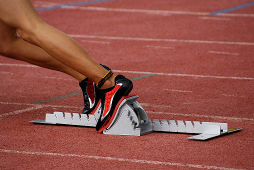female athlete starts a race from a starting block.