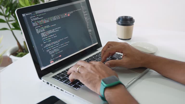 programmer man writing program code sitting at workplace in office