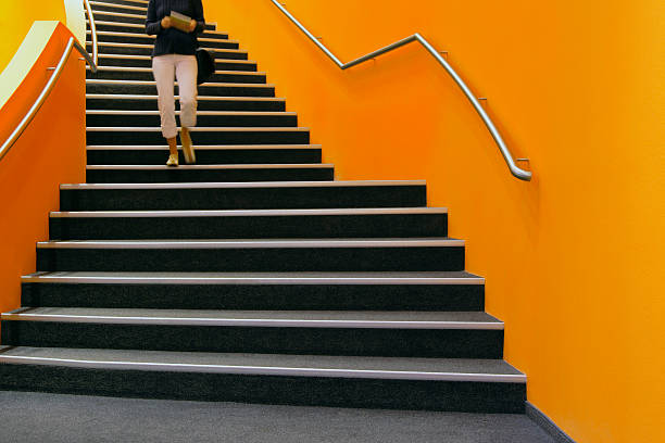 joven mujer caminar por escalera de orange, libro de lectura - orange wall fotografías e imágenes de stock