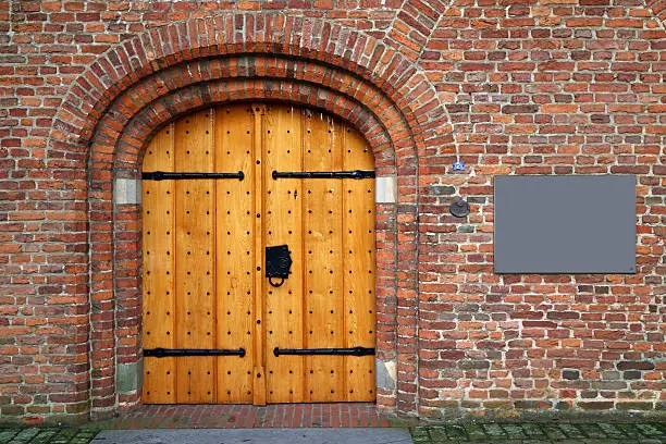 Old solid wooden doors of a dutch church with blank sign on the wall. Church is located in 's Heerenberg in the Netherlands and was founded as a chapel in the 13th century.Shot with EOS 5D + 42 mm (Tamron 28-75 mm)