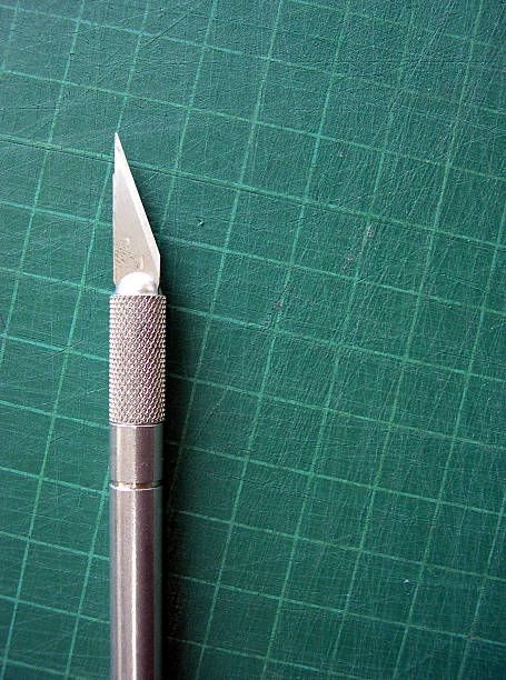 Cutting Mat and Knife A graphic designers knife on a self healing cutting mat. There is a lot of room for text or copy and the grid marks actually draw attention to the emtpy space becuase of the angles.Thanks for checking it out! knurl stock pictures, royalty-free photos & images