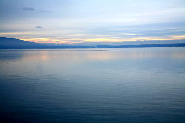 A scenic view of a tranquil lake with a rocky shore at cloudy sunset