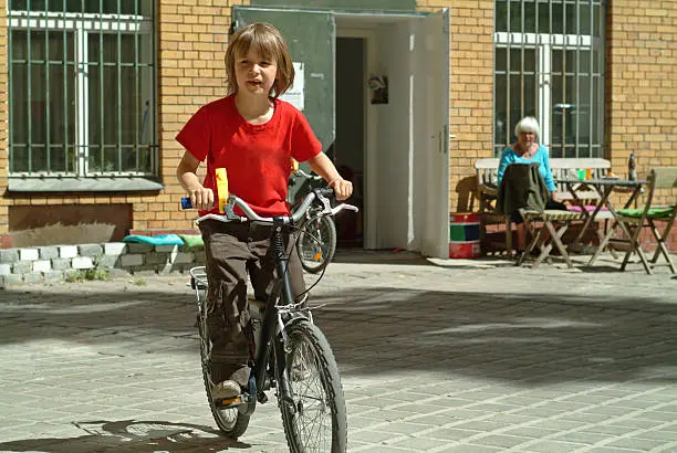 Photo of Young boy cycling with grandma watching