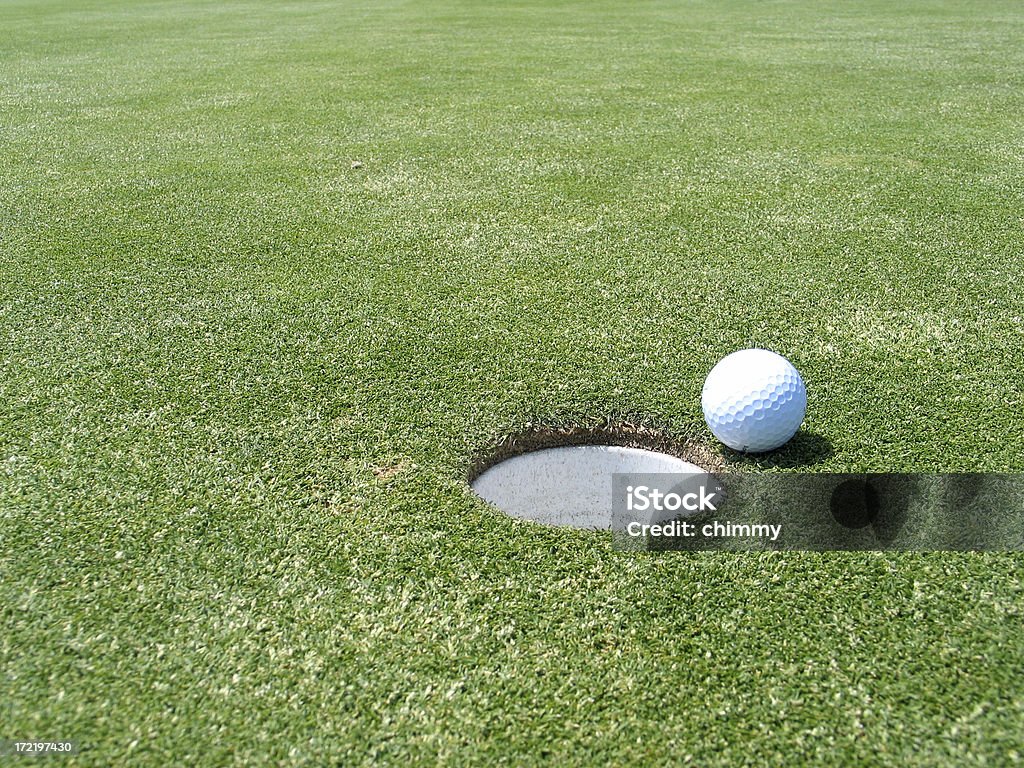 Golf Ball near the hole Golfball next to the cup on the green. Approaching Stock Photo