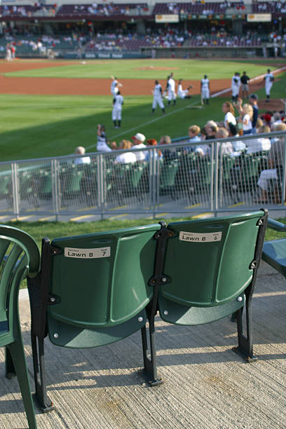 Baseball Stadium Seats, Dayton, Ohio "Baseball Stadium Seats. Focus point is the chair - people and field are soft focus. Fifth Third Stadium in Dayton, Ohio. Back of seat says Section Lawn B Seat 7." baseball stadium chairs stock pictures, royalty-free photos & images