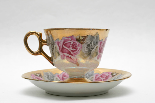 gold trimmed antique teacup and saucer with floral pattern