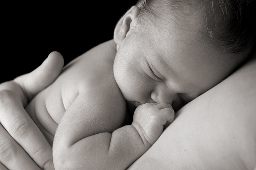 Newborn baby sleeping peacefully on daddy.