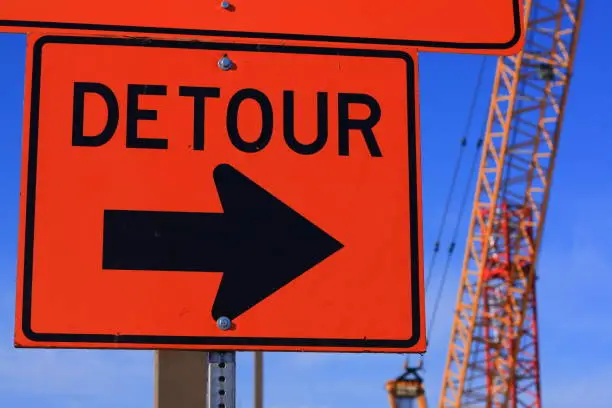 Detour street sign with crane and blue sky in background