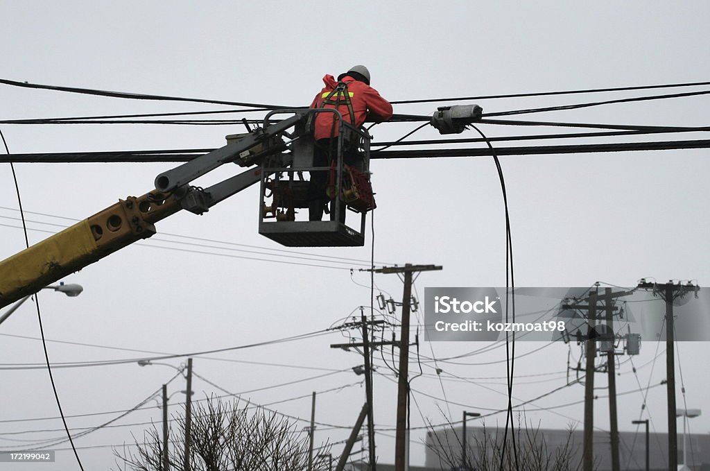 Hydro Maintenance Hydro person working from a boom bucket installs new cables on hydro line. Blackout Stock Photo