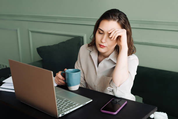 Work-Induced Stress. Tired Middle-Aged Woman with Laptop. Stress and Fatigue. Middle-Aged Woman Struggles with Laptop Work. Overworked and Drained. Middle-Aged Woman with Coffee and Laptop. estrés inducido por el trabajo. mujer cansada de mediana edad con computadora portátil. estrés y fatiga. una mujer de mediana edad tiene dificultades con el trabajo con la computadora portátil. sobrecargado de trabajo y agotado. mujer de mediana edad c