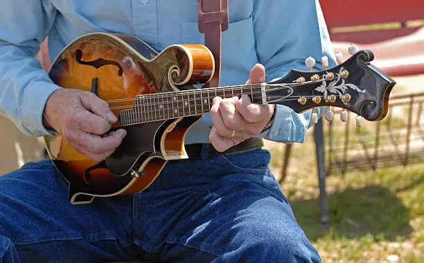 Old timer picks a bluegrass tune on a mandolin at a folk music festival. Need photos representing music