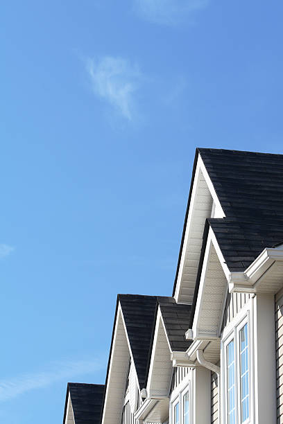 Row of roofs and eaves of homes with blue sky Roof peaks on an anonymous townhome, ready for a buyer. eaves stock pictures, royalty-free photos & images