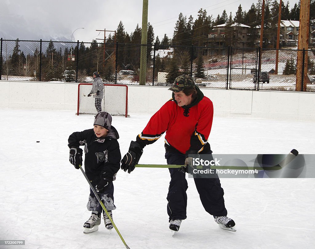 Vater und Sohn spielen & Eishockeyspieler auf der Eislaufbahn im Freien - Lizenzfrei Vater Stock-Foto