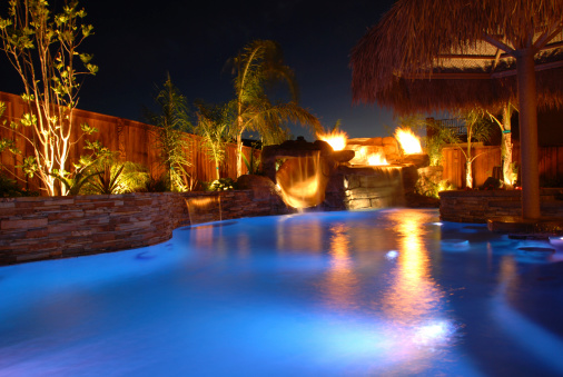 A swimming pool and palapa dramatically lit with fiber optic lights.