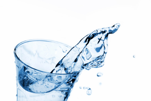 Water being poured into Glass against White Background, red in the bottom of the glass