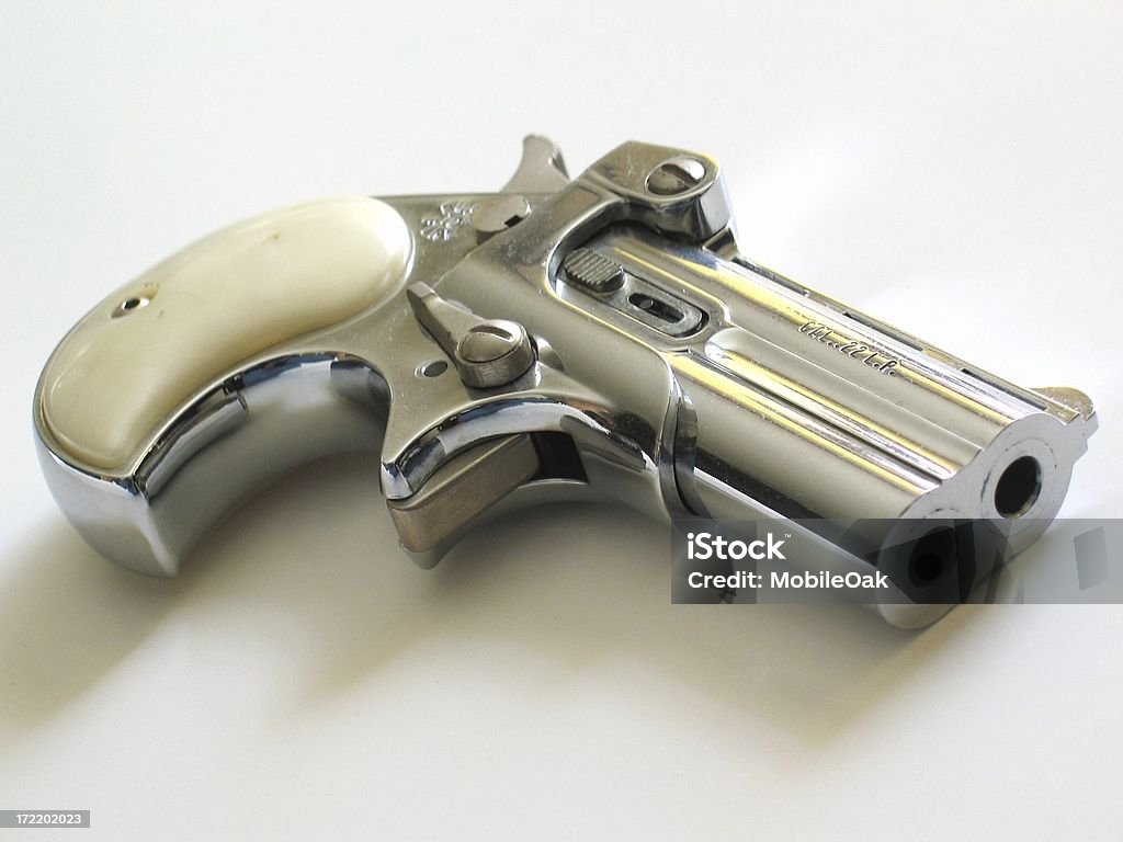 Deringer Pistol A pocket pistol used by scoundrels playing poker in the 1800s.<br><br>Unfortunately the shadow was trimmed on the left and there is a slight blue reflection (probably the photographer's jeans) on the handle of the gun. Antique Stock Photo