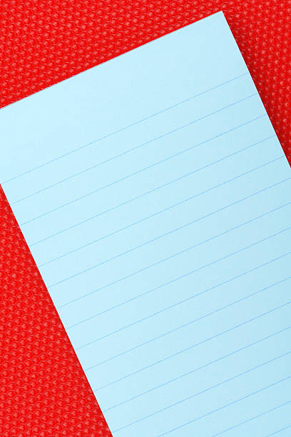 Blue notepad on red acrylic surface stock photo