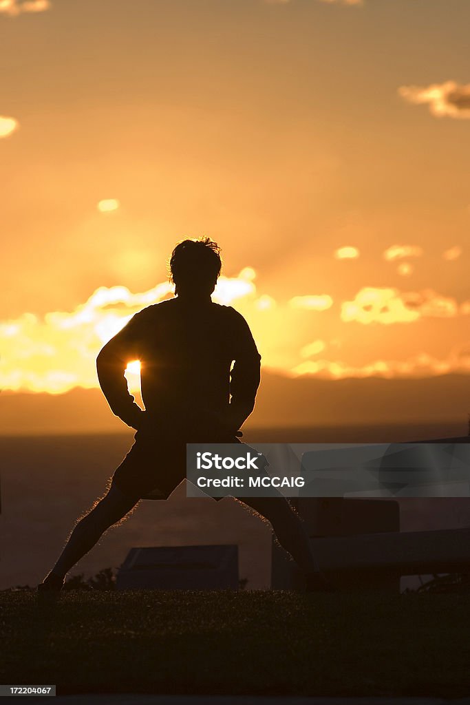 SUNSET STRETCH A man enjoys an ocean sunset while stretching. Active Lifestyle Stock Photo