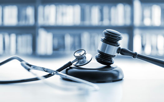 The picture shows a judge's gavel, a stethoscope and a blurred wall of books in the background. Concept for: The image shows a judge's gavel, a stethoscope and a blurry wall of books in the background. Concept for: Medical jurisprudence. legal definition of medical malpractice