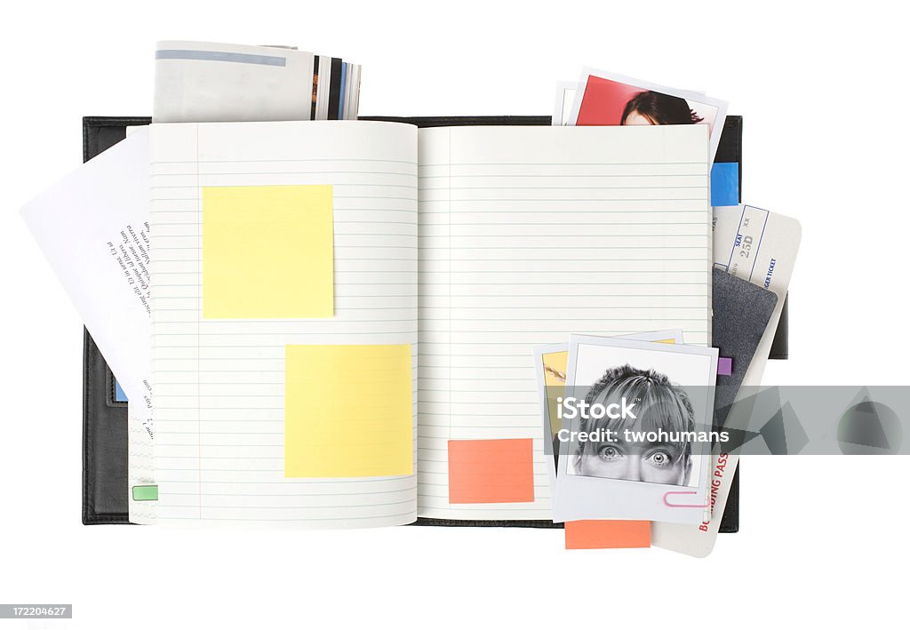 Planning a trip Opened notebook with blank post-it, polaroids, boarding pass, magazine, passport . Note that all material (images, boarding pass; document were created by us. White background Personal Organizer Stock Photo