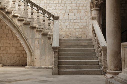 Stone stairs with Roman styling in a courtyard.