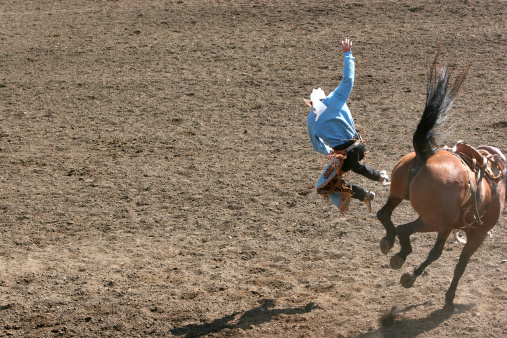 Cowboy was bucked off the horse at the rodeo.