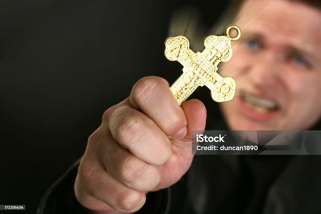 Crucifix Picture of a man holding a crucifix.  There is latin words on the cross and Christian symbols. You can find more photographs of this model in Exorcism Stock Photo