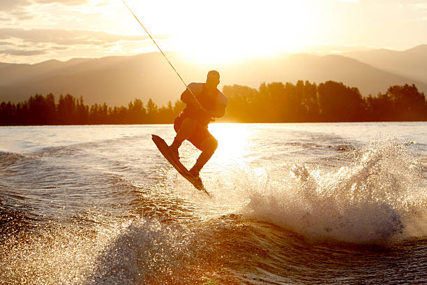 wakeboarder at sunrise "A wakeboarder catches air during a sunrise session on Lake Pend Oreille, near Sandpoint, Idaho" punting stock pictures, royalty-free photos & images