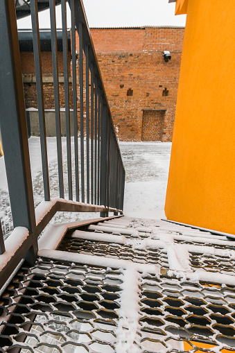 Fire exit stair of large factory building in winter season with snow. Galvanised metal stair step.