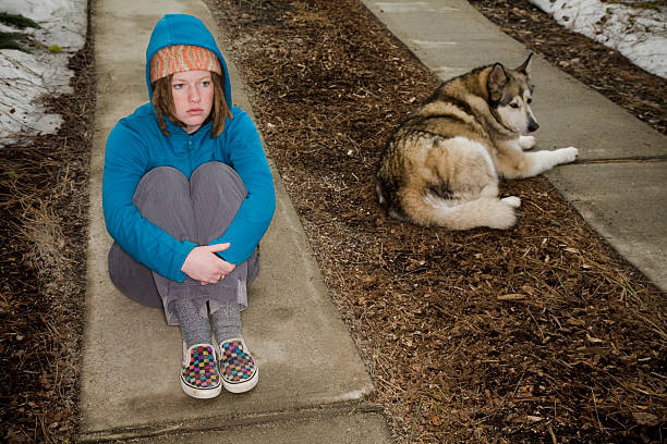 A grounded girl sits outside feeling dejected.