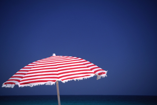 Open striped beach umbrella isolated on white