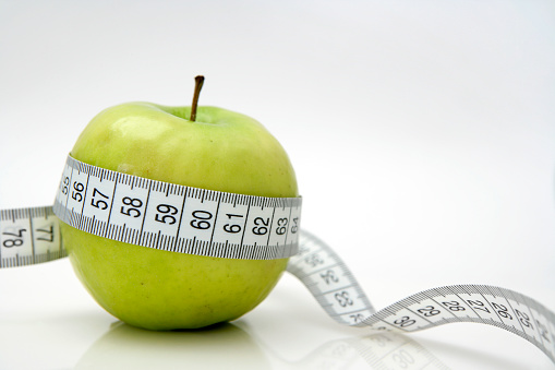 Close-up of a green apple with a measuring tape around it. High resolution - 16 Mpx.