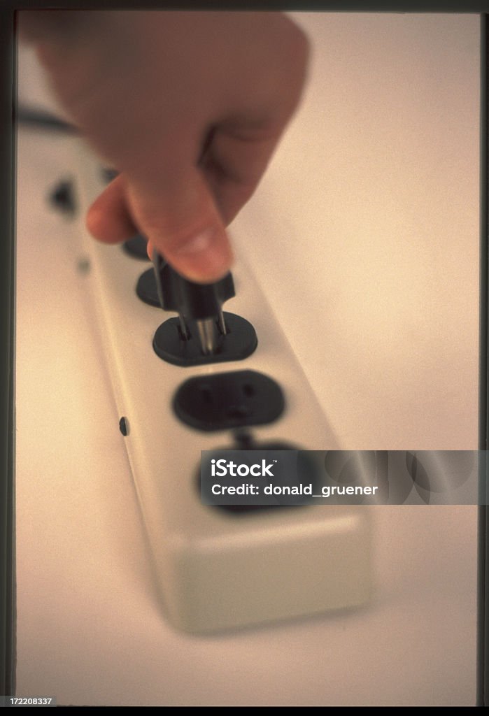 Electrical Sockets Hand plugging a cord into a power strip. Cable Stock Photo